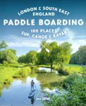 Image of Paddleboarder on river with green leafy trees grassy banks and blue sky
