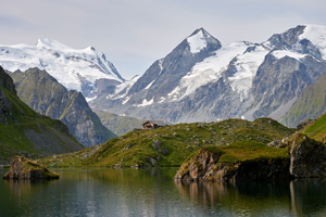 Image of snowy mountains in background with lake and hut in foreground
